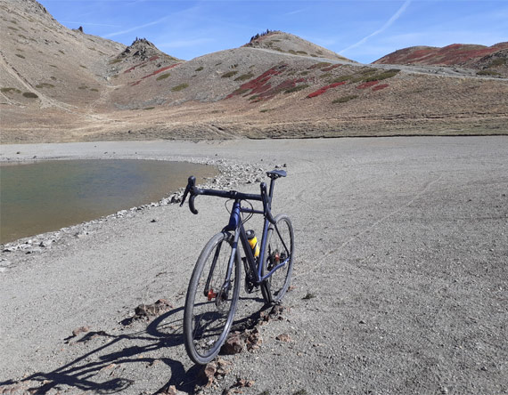 velo gravel posé contre une fontaine sous le ciel bleu du Queyras